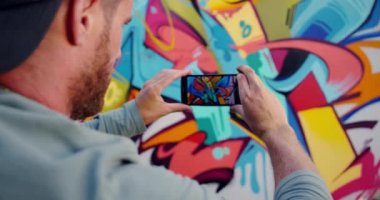 Beyaz grafiti sanatçısı cep telefonu ile grafiti duvar fotoğraf çekmek arka görünümü. Yaratıcı ve renkli grafiti duvar 4k