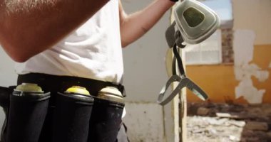 Beyaz grafiti sanatçısının güneş ışığında koruyucu maske taktığı yan görünüm. O sprey boyama 4k için hazırlanıyor