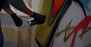 Duvarda aerosol sprey ile kafkas grafiti sanatçısı boyama yan görünümü. O koruyucu maske 4k giyiyor