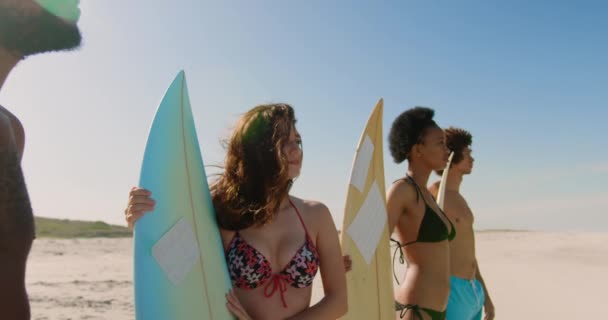 一群多民族的年轻多民族朋友站在冲浪板边看阳光4K的海滩的大海的侧视图 — 图库视频影像