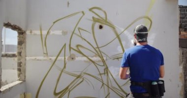 Beyaz grafiti sanatçısının güneş ışığı altında duvara baktığını görmek. O koruyucu maske 4k giyiyor