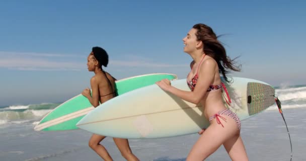 太陽の光4Kのビーチでサーフボードで走る若い多民族女性の友人の側面図 — ストック動画