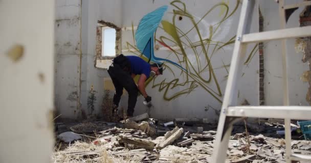 Zadní pohled na kavkazské graffiti umělecké malby s aerosolovým sprejem na stěně. On nosí ochrannou masku 4k