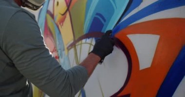 Duvarda aerosol sprey ile kafkas grafiti sanatçısı boyama yan görünümü. O koruyucu maske 4k giyiyor