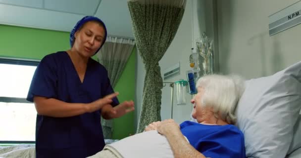 病棟で活動中の高齢者と交流するアフリカ系アメリカ人看護師の正面図 彼女は彼女の4Kを慰めている — ストック動画