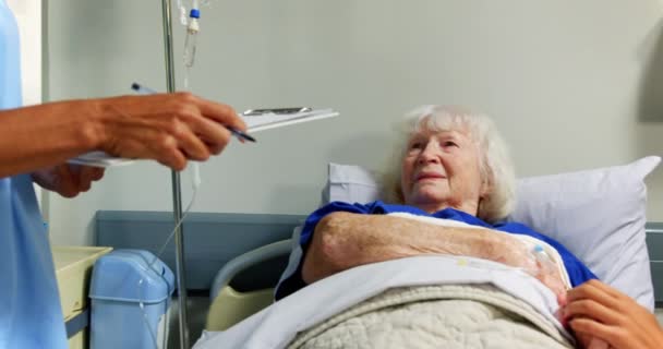 病院で病棟の先輩患者と交流する白人女性医師の側面図 病院のベッド4Kでリラックスするシニア患者 — ストック動画