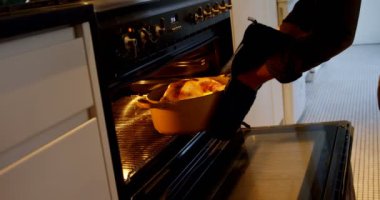 Kafkas adamın orta kesiminde evde mutfakta fırında tavuk pişirme izliyor. 4k