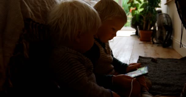在家中使用数字平板电脑的白种兄弟姐妹的侧面视图 他们坐在地板上4K — 图库视频影像