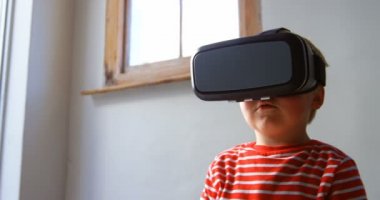 Evde oturma odasında sanal gerçeklik kulaklık kullanarak Kafkas çocuğun ön görünümü. O kanepede 4k oturuyor