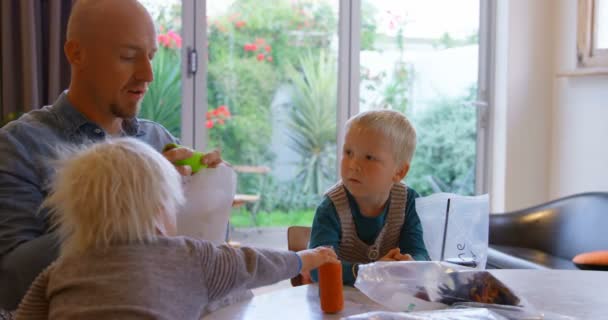 白种人父亲的侧视图显示他的孩子们纱卷轴在客厅在家里 他们坐在桌子4K — 图库视频影像