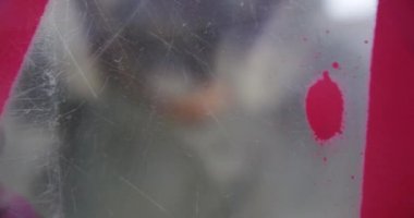 Cam duvara grafiti sanatçısı sprey boya yakın çekim. Kırmızı sprey boya 4k kullanarak yaratıcı sanatçı