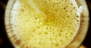 Siyah arka plana karşı cam dökülen bira yakın çekim. Kabarcıklar ve köpük cam şekillendirme. 4k