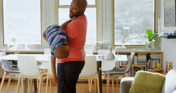 从侧面看非裔美国人的父亲和儿子在一个舒适的家里玩的很开心 父亲抱着他的儿子 — 图库视频影像