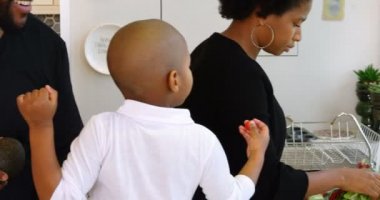 Afro-amerikan ailesinin evde yemek hazırlarken ki yan görüntüsü. Anne lavaboda sebze yıkıyor. 4k