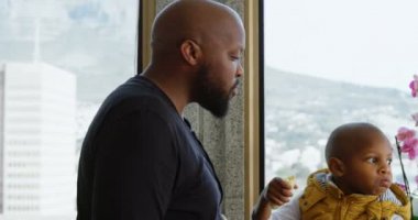 Afrika kökenli Amerikalı baba ve oğulun evde muz yemesi. Baba oğluna muz kabuğu veriyor. 4k