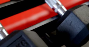 Fitness stüdyosunda bir rafta dambılların yakın çekim. Dumbbells arka arkaya düzenlenmiştir. 4k