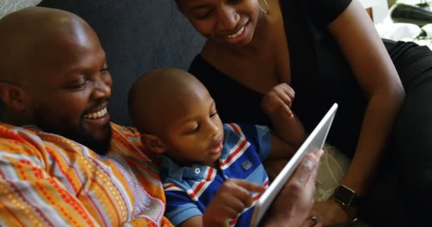 在家里 看到非洲裔美国人父母和儿子在床上用数字平板电脑微笑的镜头 — 图库视频影像
