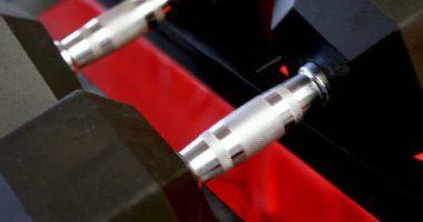 Fitness stüdyosunda bir rafta dambılların yakın çekim. Dumbbells arka arkaya düzenlenmiştir. 4k
