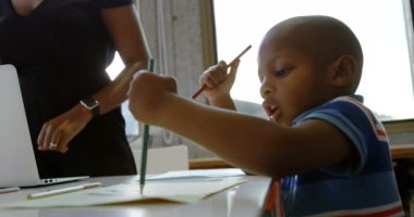 Rahat bir evde kağıt üzerinde çizim Afrikalı Amerikalı çocuk yan görünümü. Masada oturuyor. 4k