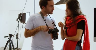 Beyaz erkek fotoğrafçının ön görünümü fotoğraf stüdyosunda dijital fotoğraf makinesinde kadın modele fotoğraf gösteren. Birbirleriyle etkileşime giriyorlar. 4k