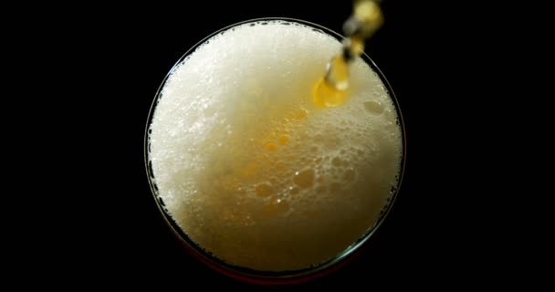 黒い背景にガラスに注がれたビールの高角ビュー ガラスの泡と泡形成 — ストック動画