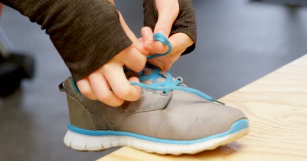 フィットネススタジオで靴ひもを結ぶ美しい白人女性の側面図 彼女は運動の準備をしている — ストック動画