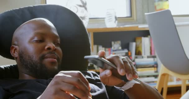 Вид Сбоку Африканского Мужчину Пользующегося Смартфоном Уютном Доме Расслабляется Стуле — стоковое видео