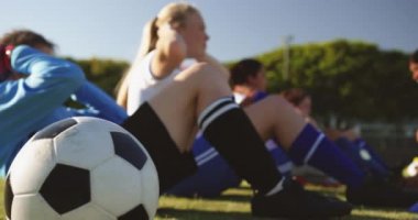 Karışık yarış kaptanı futbol sahasında eğitim verirken çeşitli kadın futbol takımının yan görünümü egzersizler kadar oturup yapıyor. 4k