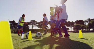 Farklı kadın futbolcuların yan görünümü yere atlarken, Kafkas takım kaptanı güneşli bir günde futbol sahasında antrenman yaptı. 4k