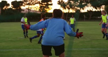 Beyaz kadın oyuncu futbol sahasına düşerken, topu geçen farklı kadın futbolcuların ön görünümü. 4k