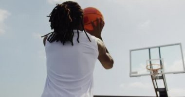 Basketbol sahasında basketbol oynayan Afrikalı-Amerikalı basketbolcu düşük açı görünümü. Basketbol potasında top atıyor.