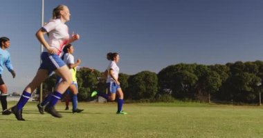 Kafkas takım kaptanı güneşli bir günde futbol sahasında talimatlar verirken farklı kadın futbol takımının yan görünümü. 4k