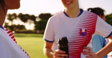 Beyaz beyaz kadın futbolcunun ön görünümü futbol sahasında karışık ırk takım arkadaşıyla konuşurken mola veriyor. 4k