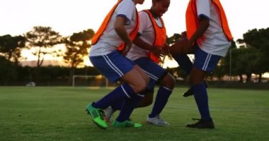 Turuncu yelekli farklı kadın futbolcuların ön görünümü futbol sahasında havada kollarla tezahürat yapıyor. 4k