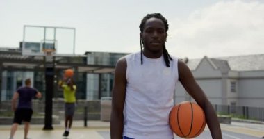 Afro-Amerikan basketbolcu mahkemede basketbol ile ayakta ön görünümü. O kamera 4k bakıyor