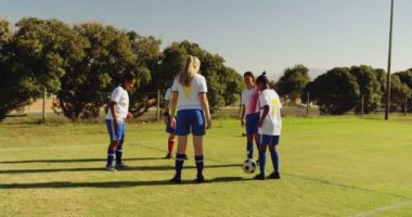 Güneşli bir günde futbol sahasında bir daire içinde topu geçen çeşitli kadın futbol takımı ön görünümü. 4k