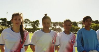 Güneşli bir günde futbol sahasında yan yana duran farklı kadın futbol takımının ön görünümü. 4k