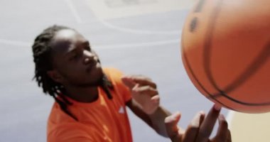 Afro-Amerikan basketbolcu mahkemede basketbol ile oynarken yüksek açı görünümü. O bir parmak 4k basketbol dönüyor