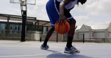 Basketbol sahasında basketbol oynayan Afrikalı-Amerikalı basketbolcu düşük açı görünümü. Basketbol 4k'den kaçıyor.