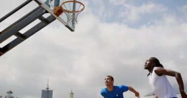 Basketbol sahasında basketbol oynayan çok ırklı basketbolcuların düşük açılı görünümü. Onlar bir gol 4k yapıyoruz