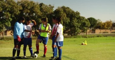 Güneşli bir günde futbol sahasında taktikleri tartışan çeşitli kadın futbol takımı ön görünümü. 4k