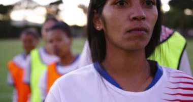 Futbol sahasında onu çeşitli kadın futbol takımının önünde duran karışık ırk kadın futbolcu portresi. 4k