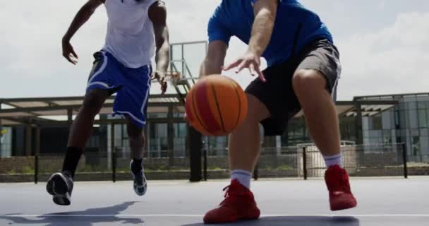 バスケットボールコートでバスケットボールをしている多民族バスケットボール選手の低角度ビュー 彼らはバスケットボール4Kをかわしている — ストック動画