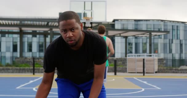 バスケットボールコートでバスケットボールをしているアフリカ系アメリカ人バスケットボール選手の正面図 彼はバスケットボール4Kをかわしている — ストック動画