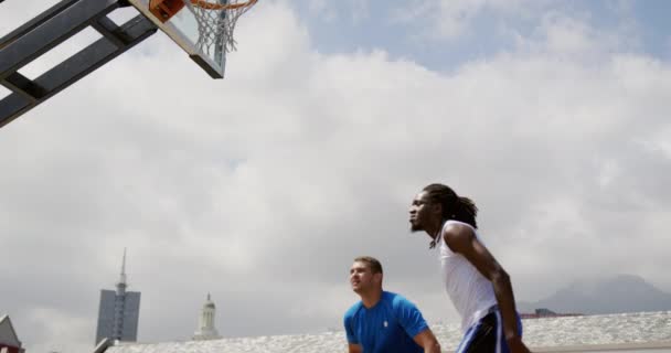 バスケットボールコートでバスケットボールをしている多民族バスケットボール選手の低角度ビュー 4Kでゴールを決める — ストック動画