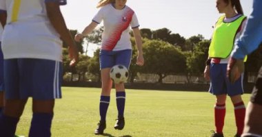 Güneşli bir günde futbol sahasında bir daire içinde topu geçen çeşitli kadın futbol takımı ön görünümü. 4k