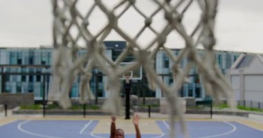 Basketbol sahasında basketbol oynayan Afrikalı-Amerikalı basketbolcu yüksek açı görünümü. Basketbol potası 4k yakın çekim