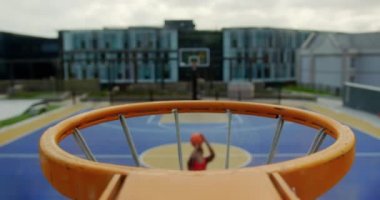 Basketbol sahasında basketbol oynayan Afrikalı-Amerikalı basketbolcu yüksek açı görünümü. Basketbol potası 4k yakın çekim