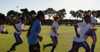 Güneşli bir günde futbol sahasında lapse çalışan aktif çeşitli kadın futbol takımının Yan görünümü. 4k