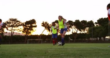 Beyaz-beyazlı kadın futbolcunun, futbol sahasında Afrikalı-Amerikalı bir oyuncu tarafından düşürülmesinin ön görünümü. 4k